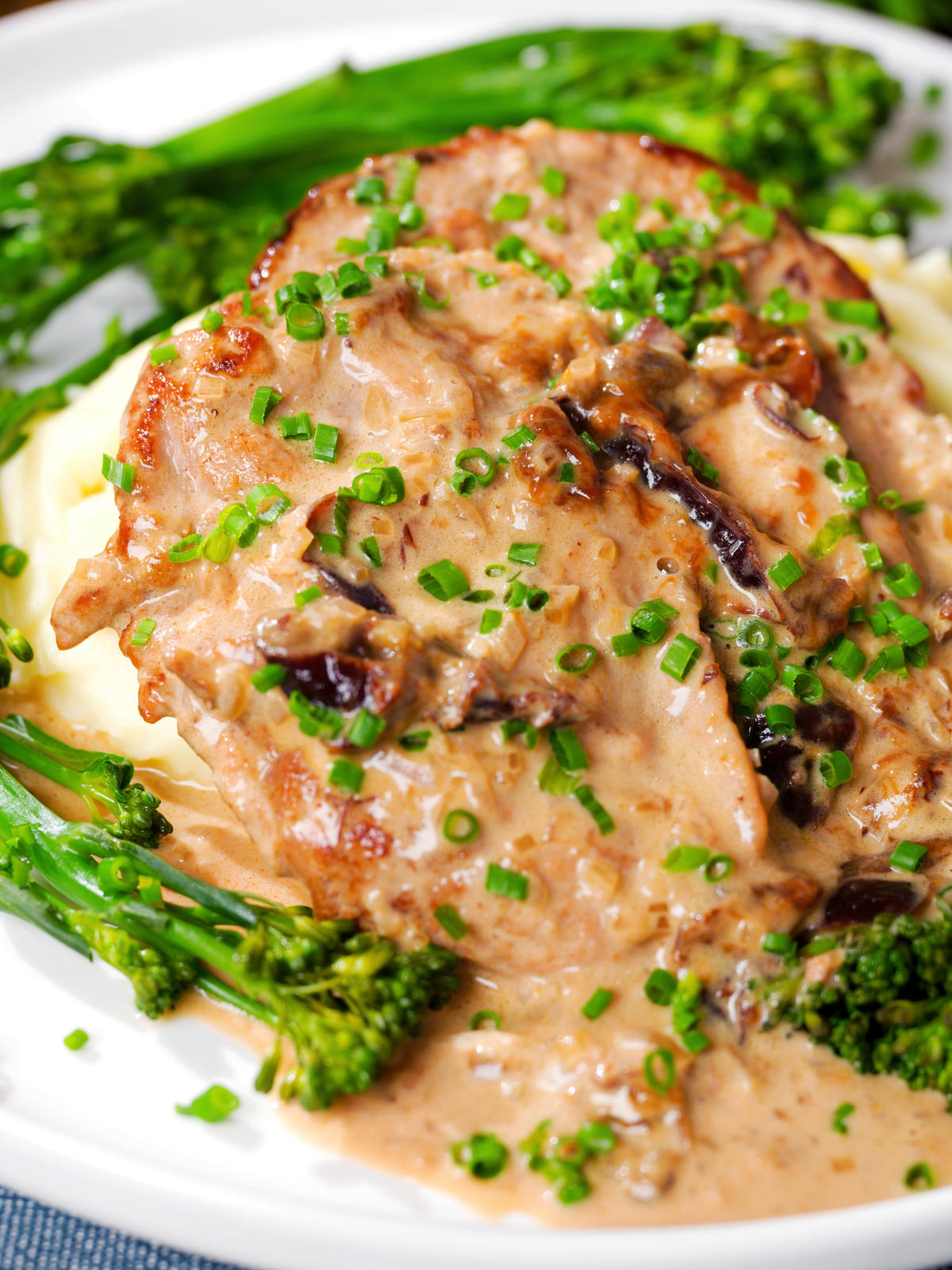 Close-up pork tenderloin with prunes and brandy cream sauce, mashed potato and tenderstem broccoli.