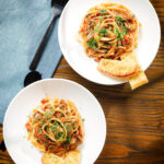 Overhead tomato and mushroom pasta on a fork served with garlic bread.