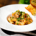 Tinned tuna tomato pasta (rigatoni) with capers, served with garlic bread.