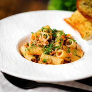 Tinned tuna tomato pasta (rigatoni) with capers, served with garlic bread.