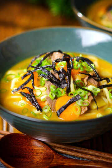 Japanese curry udon soup with beef and vegetables, nori and spring onions.