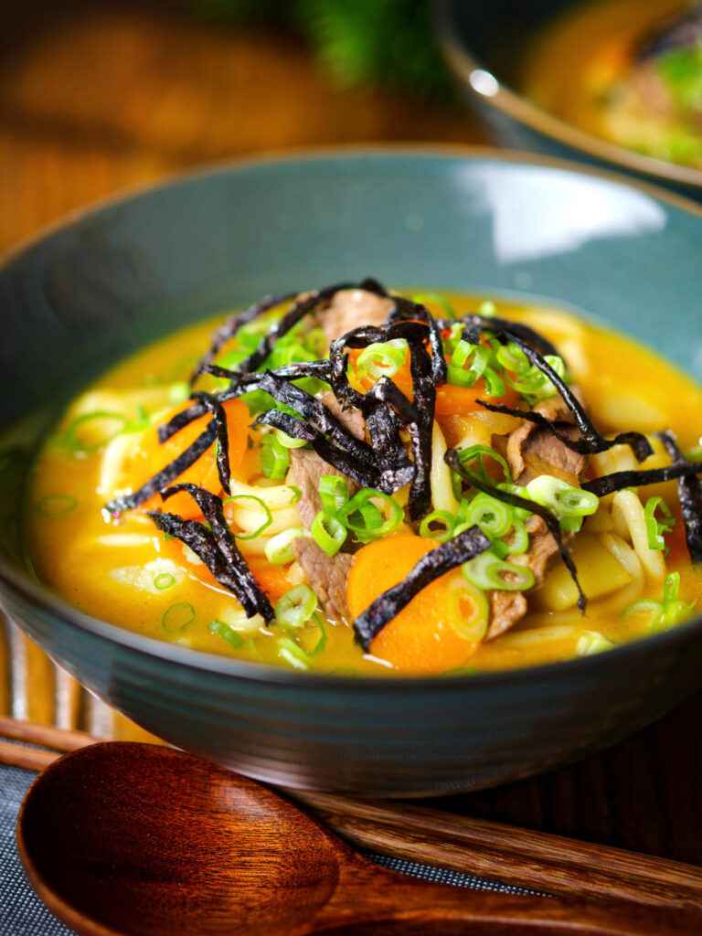 Japanese curry udon soup with beef and vegetables, nori and spring onions.