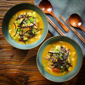 Japanese curry udon soup with beef and vegetables garnished with nori and spring onions.