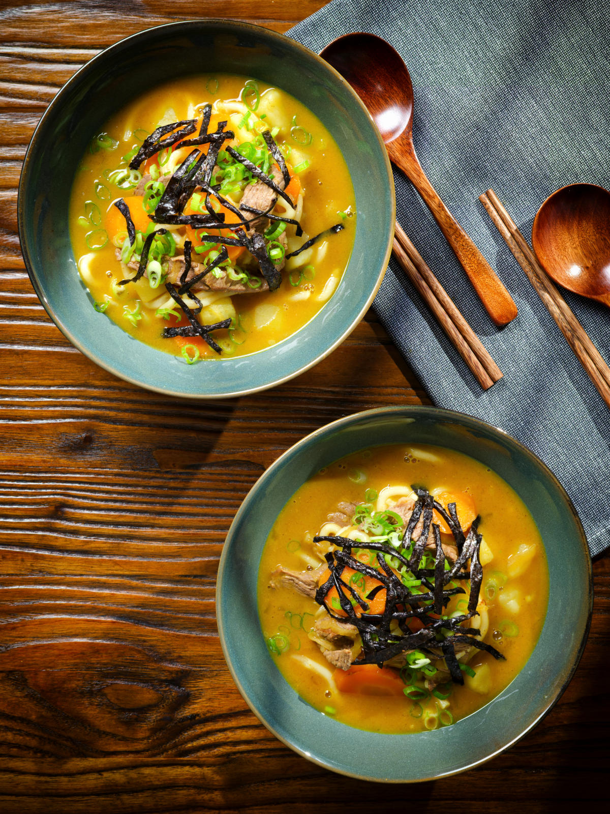 Overhead Japanese curry udon soup with beef and vegetables, nori and spring onions.