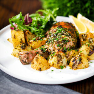 Greek-influenced roasted chicken legs with potatoes, lemon and garlic served with a side salad.