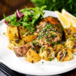 Greek roasted chicken legs with potatoes, lemon and garlic served with a side salad.