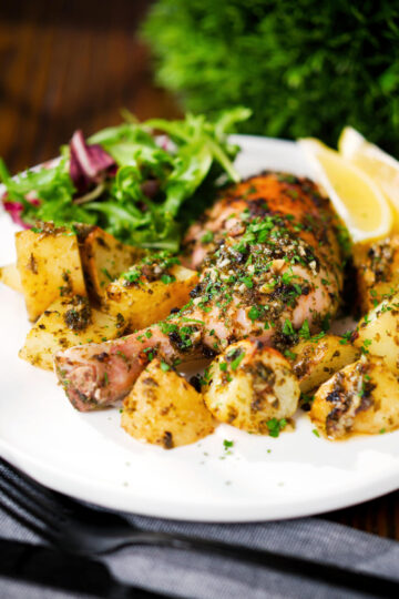 Greek roasted chicken legs with potatoes, lemon and garlic served with a side salad.