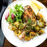 Overhead Greek roasted chicken legs with potatoes, lemon and garlic served with a side salad.