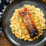Overhead hoisin sauce glazed salmon fillet served with egg fried rice.