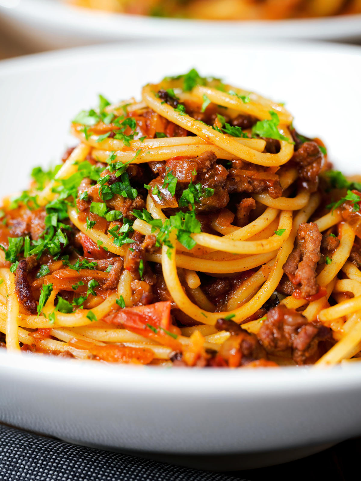 Close up makaronia me kima (Greek spaghetti bolognese) garnished with fresh parsley.