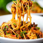Overhead makaronia me kima (Greek spaghetti bolognese) being picked up with a fork.