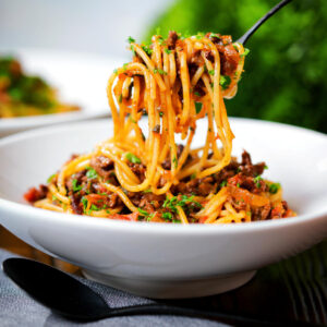 Makaronia me kima (Greek pasta bolognese) served in two bowls with chopped parsley.