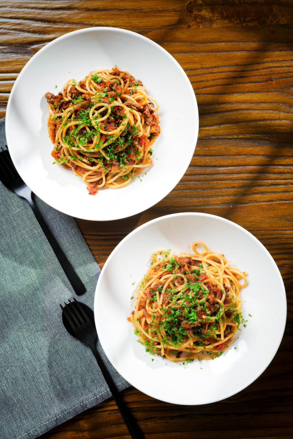 Overhead makaronia me kima (Greek spaghetti bolognese) garnished with fresh parsley.