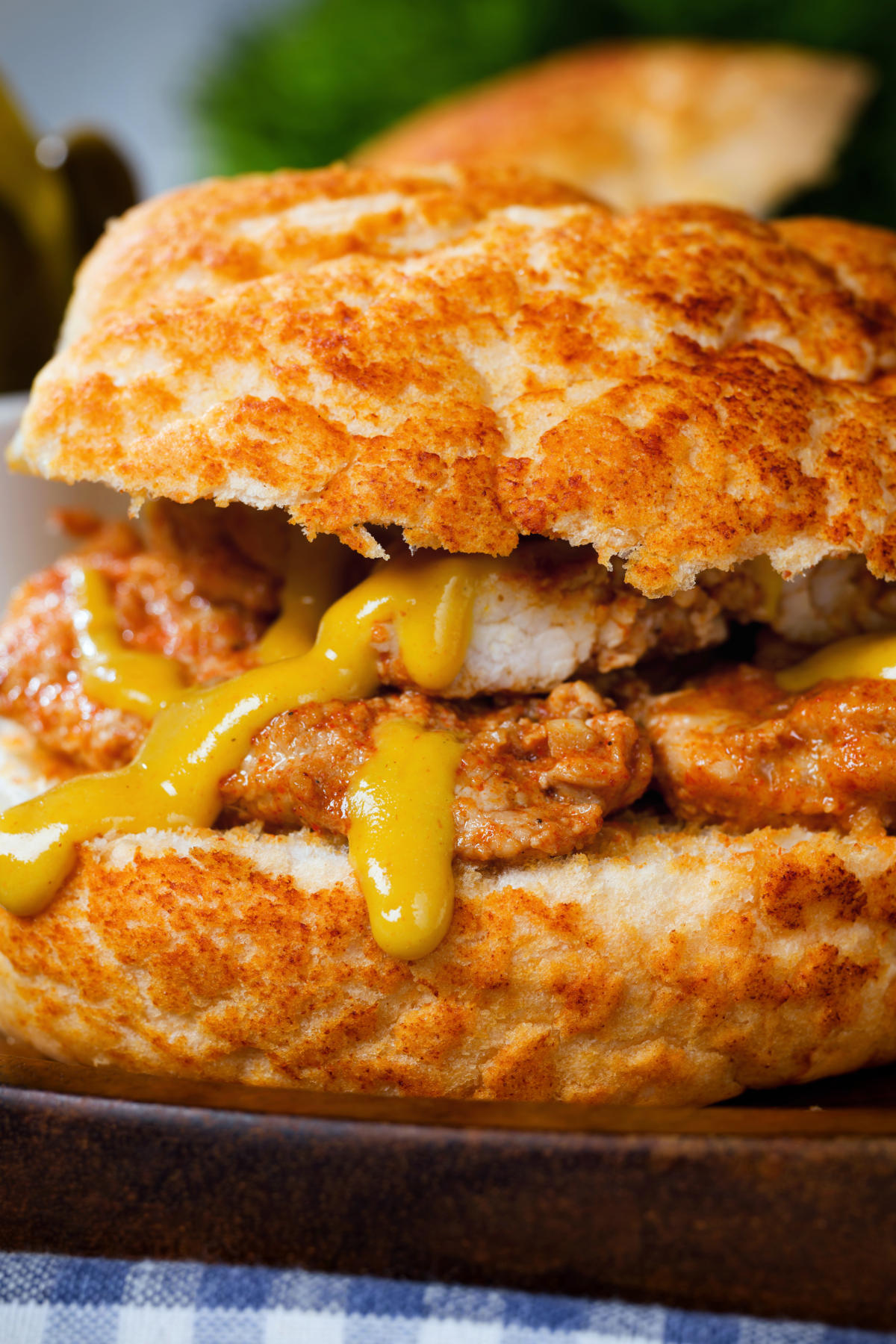 Close-up Bifana (Portuguese pork sandwich) served with mustard on a bun.