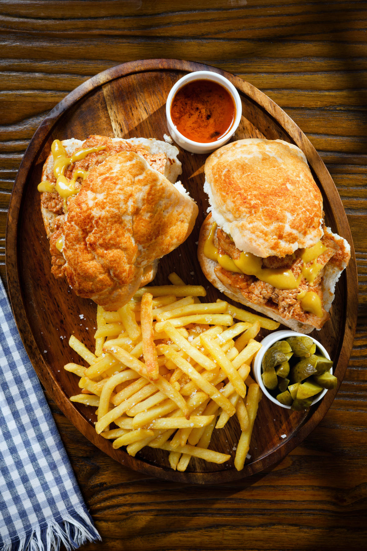 Overhead Bifana (Portuguese pork sandwich) with mustard on a bun, served with French fries and pickles.