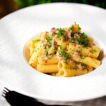 Brie and bacon pasta (rigatoni) garnished with fresh parsley.