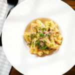 Overhead brie and bacon pasta (rigatoni) garnished with fresh parsley.