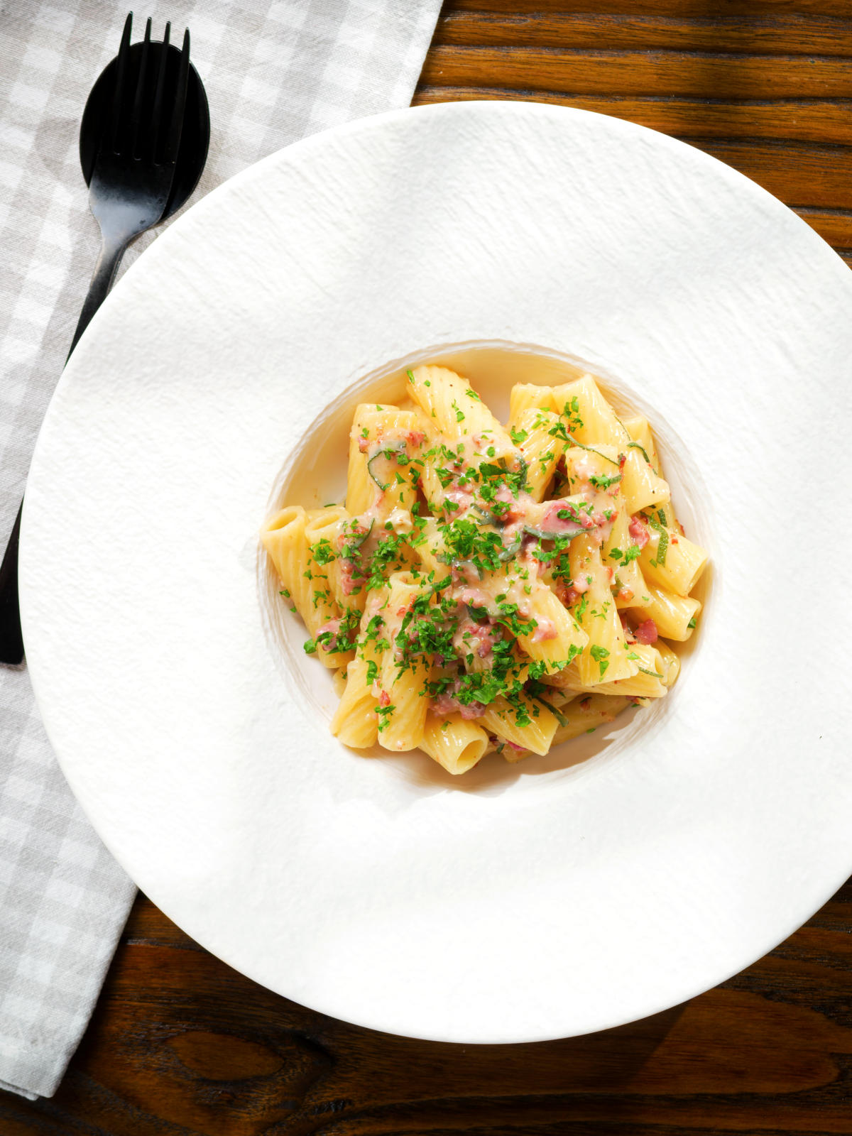 Overhead brie and bacon pasta (rigatoni) garnished with fresh parsley.