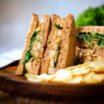 Coronation chicken (Poulet Reine Elizabeth) sandwich served with potato crisps.