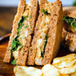 Coronation chicken sandwich served with potato crisps.