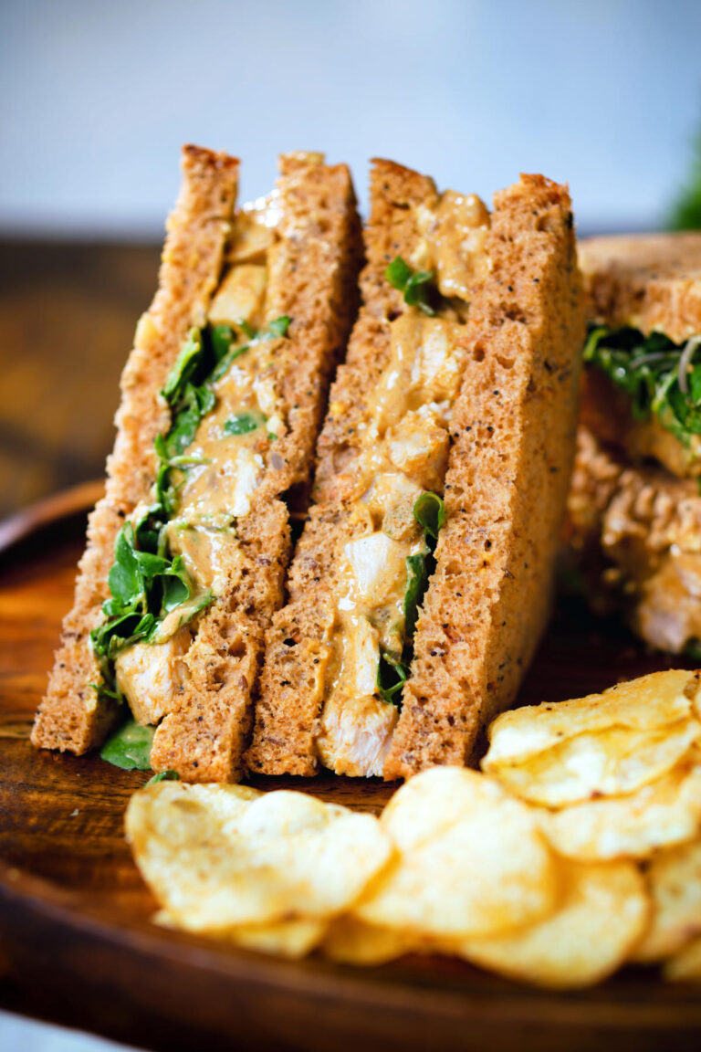 Coronation chicken sandwich served with potato crisps.