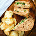 Overhead Coronation chicken sandwich served with potato crisps.