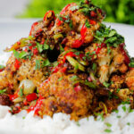 Close-up salt and pepper cauliflower bites with rice, sriracha and coriander.
