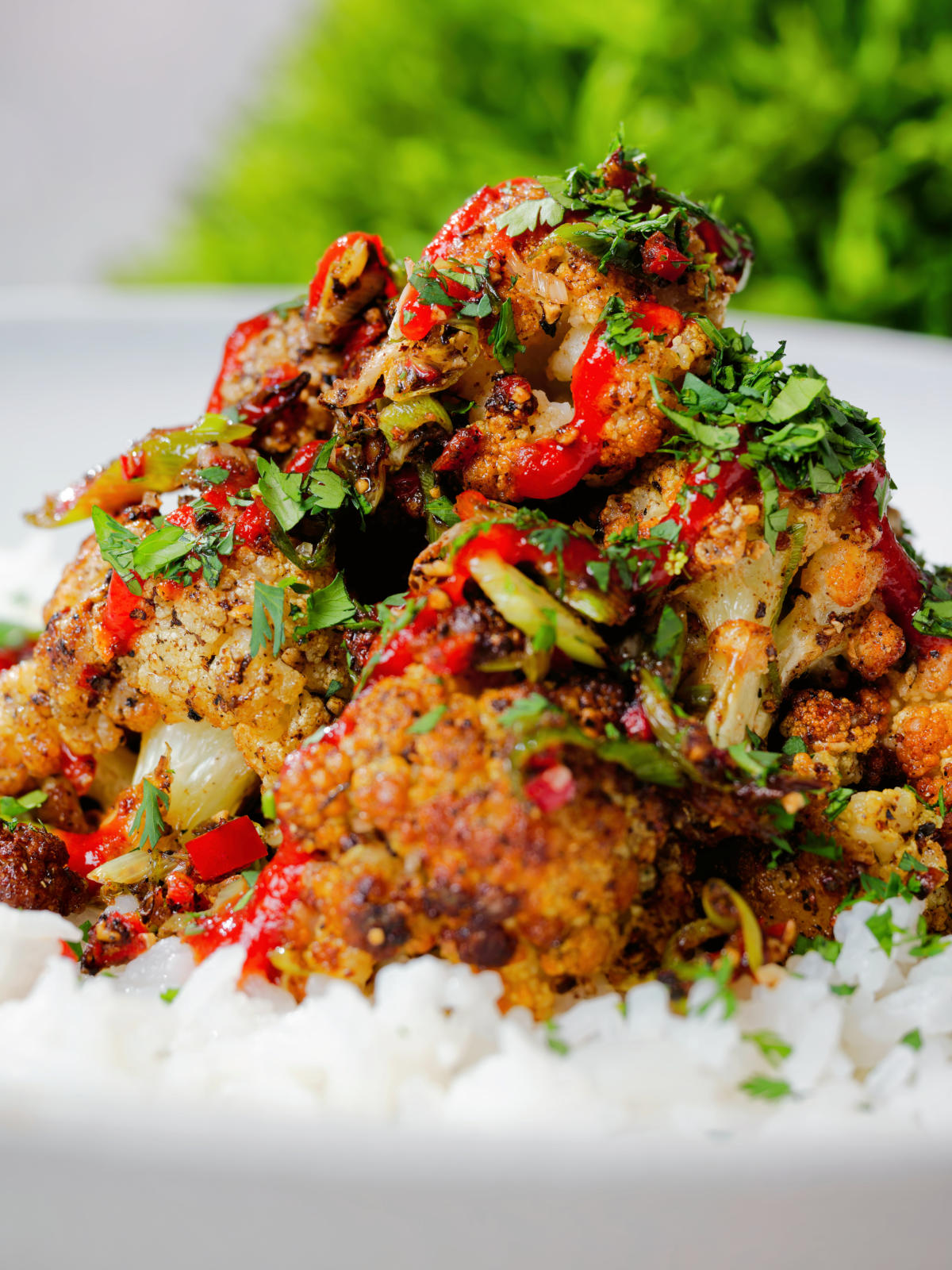 Close-up salt and pepper cauliflower bites with rice, sriracha and coriander.