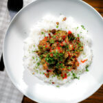 Overhead salt and pepper cauliflower bites with rice, sriracha and coriander.
