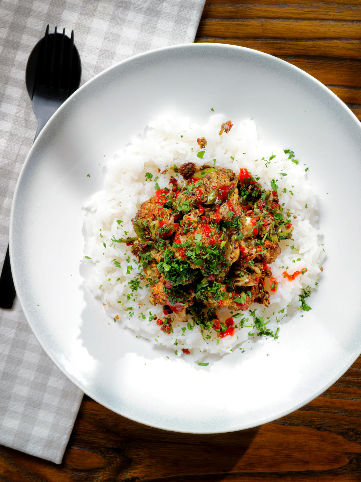 Overhead salt and pepper cauliflower bites with rice, sriracha and coriander.