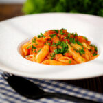 Bloody Mary Pasta (penne alla vodka), served in a white bowl with fresh parsley.