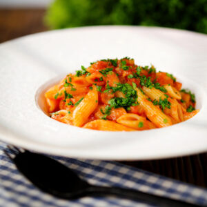 Bloody Mary Pasta (penne alla vodka), served in a white bowl with fresh parsley.
