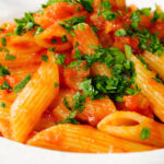Close-up Bloody Mary Pasta (penne alla vodka), served in a white bowl.