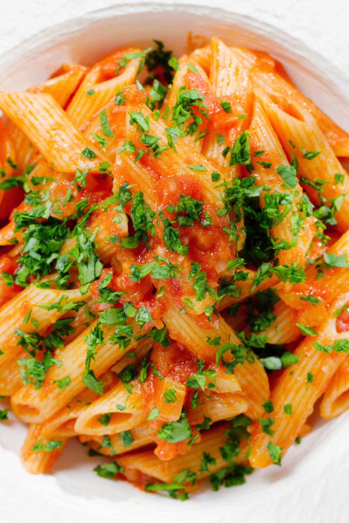 Close-up overhead Bloody Mary Pasta (penne alla vodka), served in a white bowl.