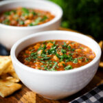 Vegan spicy chickpea and lentil soup served with fresh coriander and crispy flatbread.