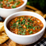 Vegan spicy chickpea and lentil soup garnished with fresh coriander.