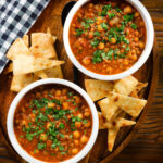 Overhead vegan spicy chickpea and lentil soup garnished with fresh coriander.