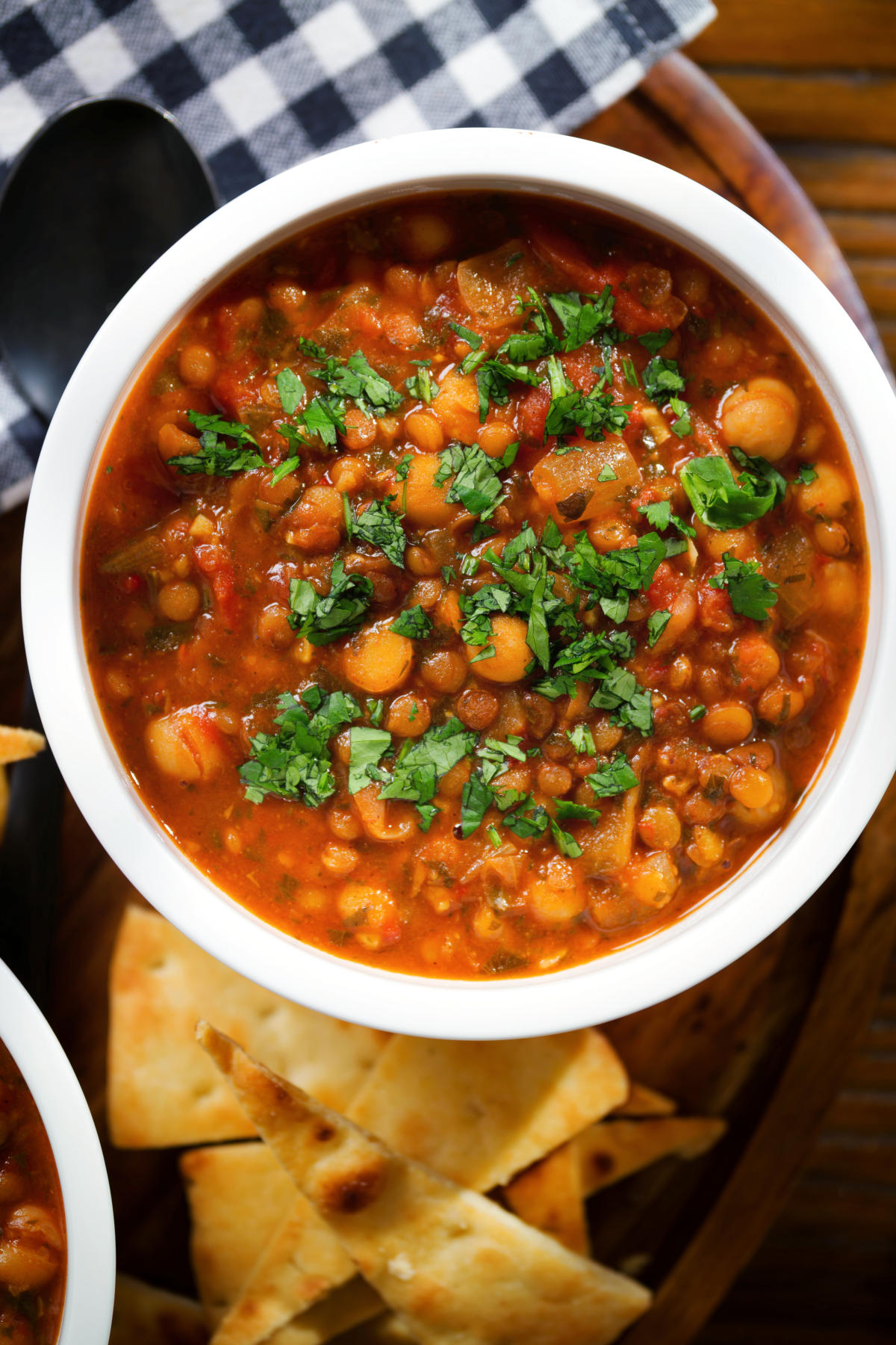 Close-up overhead vegan spicy chickpea and lentil soup garnished with fresh coriander.