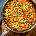 Overhead spicy one-pot sausage and rice with gochujang paste and kimchi, in a cooking pan.