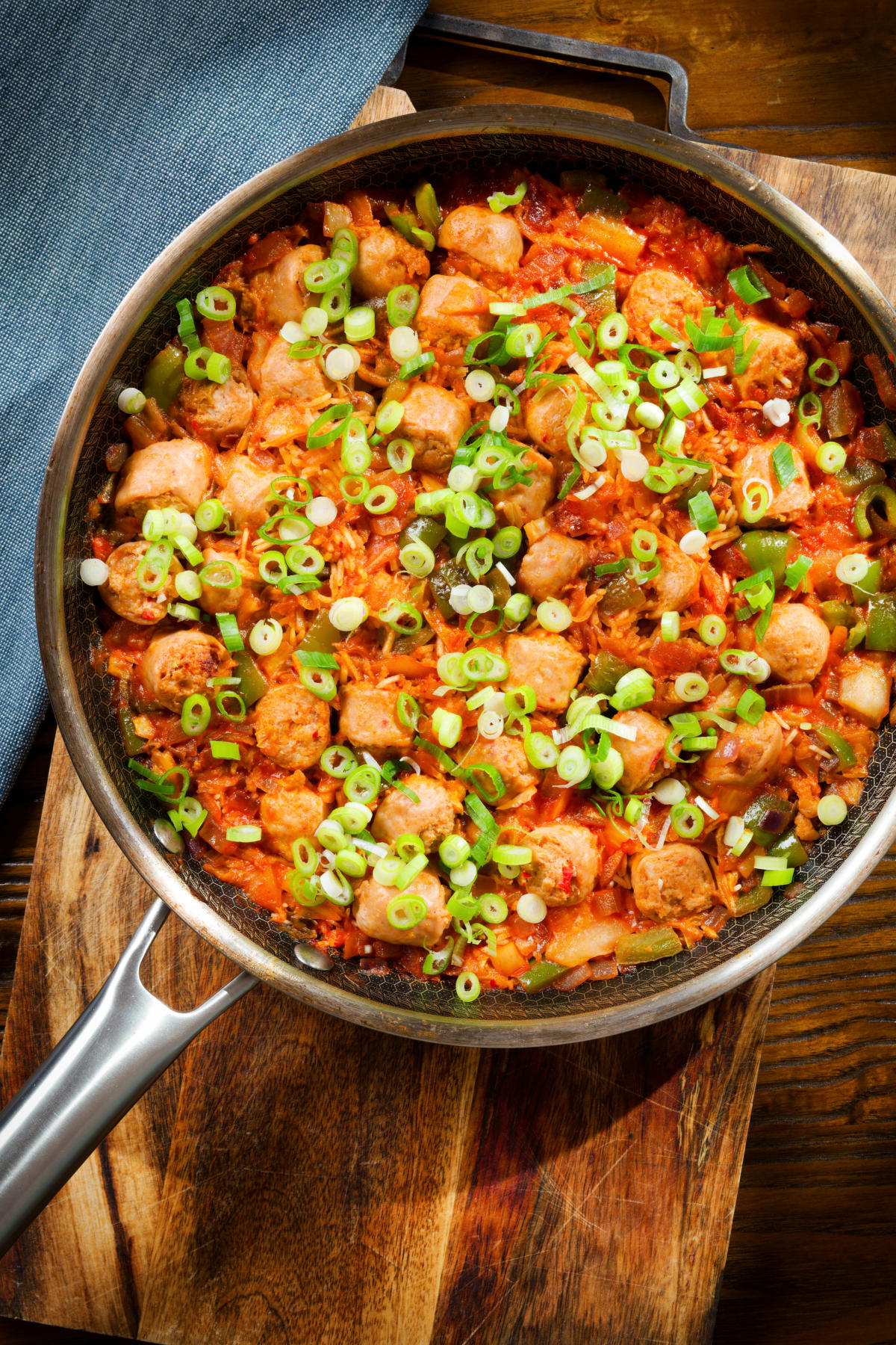 Overhead spicy one-pot sausage and rice with gochujang paste and kimchi, in a cooking pan.