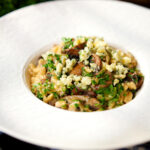One-pot stilton cheese and mushroom orzo with sage in a white bowl.