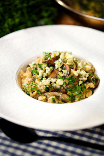One-pot stilton cheese and mushroom orzo with sage in a white bowl.