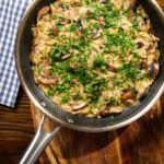 Overhead one-pot stilton cheese and mushroom orzo with sage in a pan.
