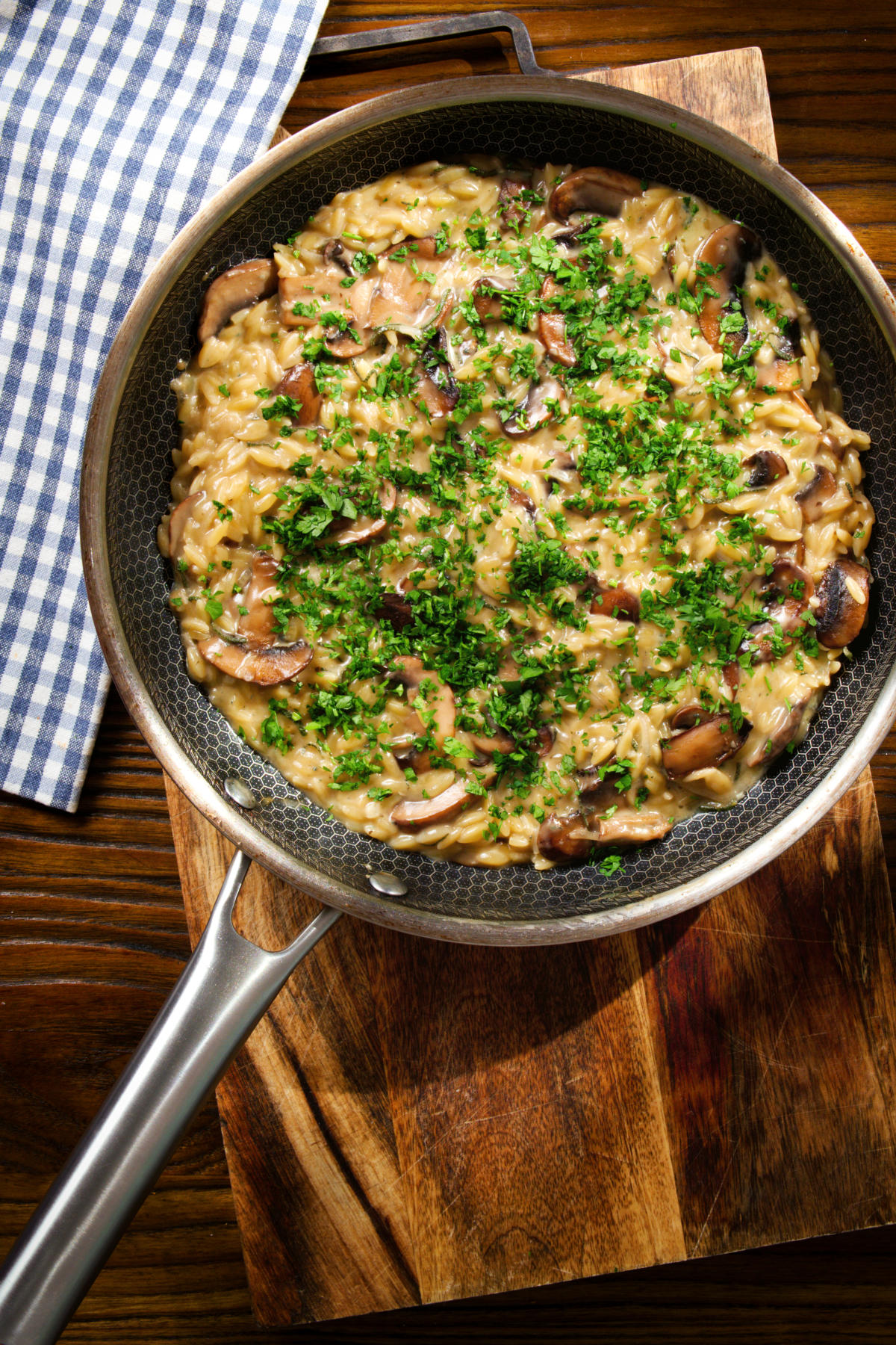 Overhead one-pot stilton cheese and mushroom orzo with sage in a pan.