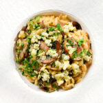 Overhead one-pot stilton cheese and mushroom orzo with sage in a white bowl.