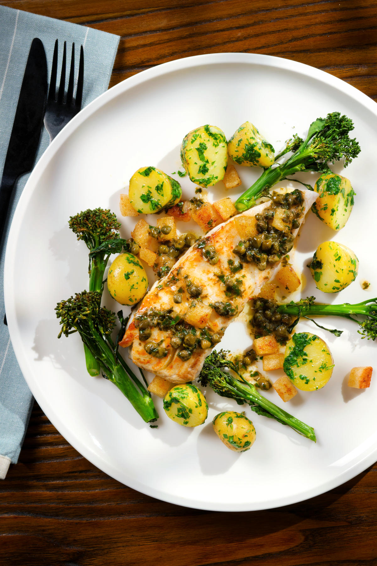 Overhead pan-fried halibut with Grenobloise sauce, buttered potatoes and tenderstem broccoli.