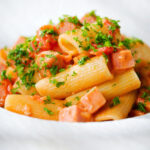Close-up Spam pasta in a tomato and Dijon mustard sauce.