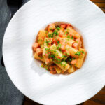Overhead Spam pasta in a tomato and Dijon mustard sauce.