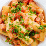 Close-up overhead Spam pasta in a tomato and Dijon mustard sauce.