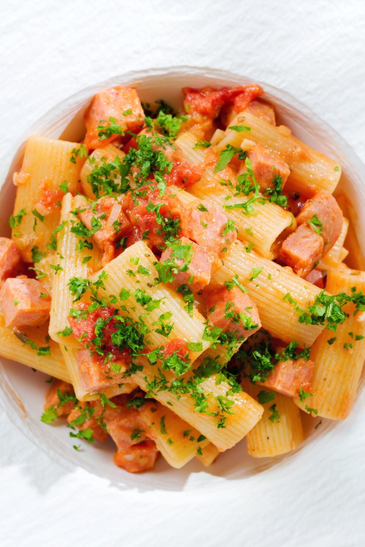 Close-up overhead Spam pasta in a tomato and Dijon mustard sauce.
